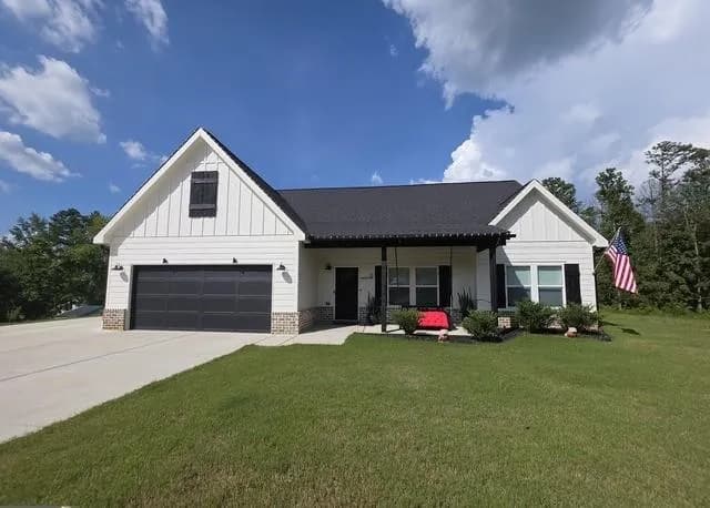 Modern inspired farmhouse with board and batten siding, a front lawn, a porch, concrete driveway, and brick siding