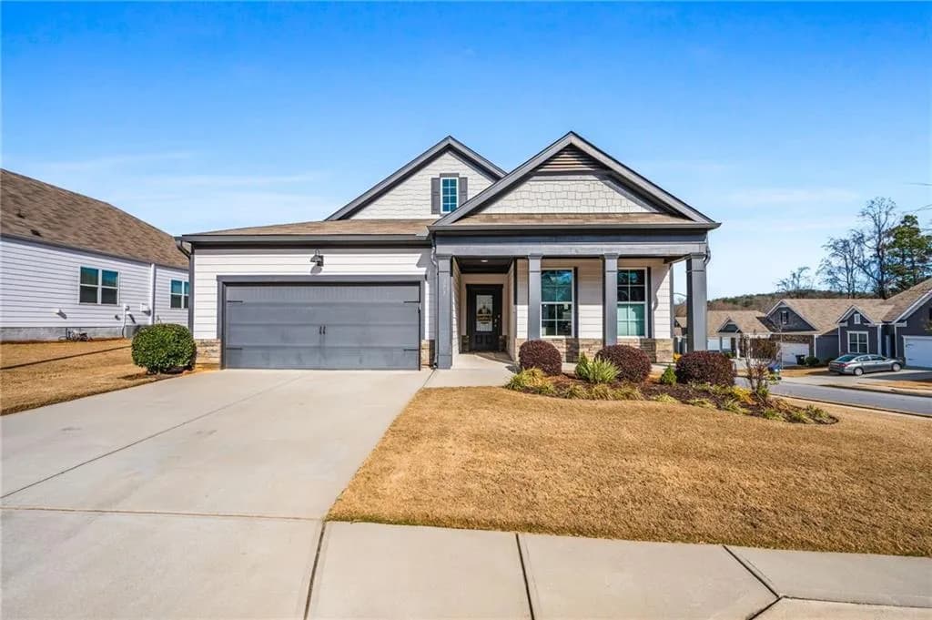 Craftsman inspired home featuring stone siding, a porch, driveway, a front lawn, and a garage