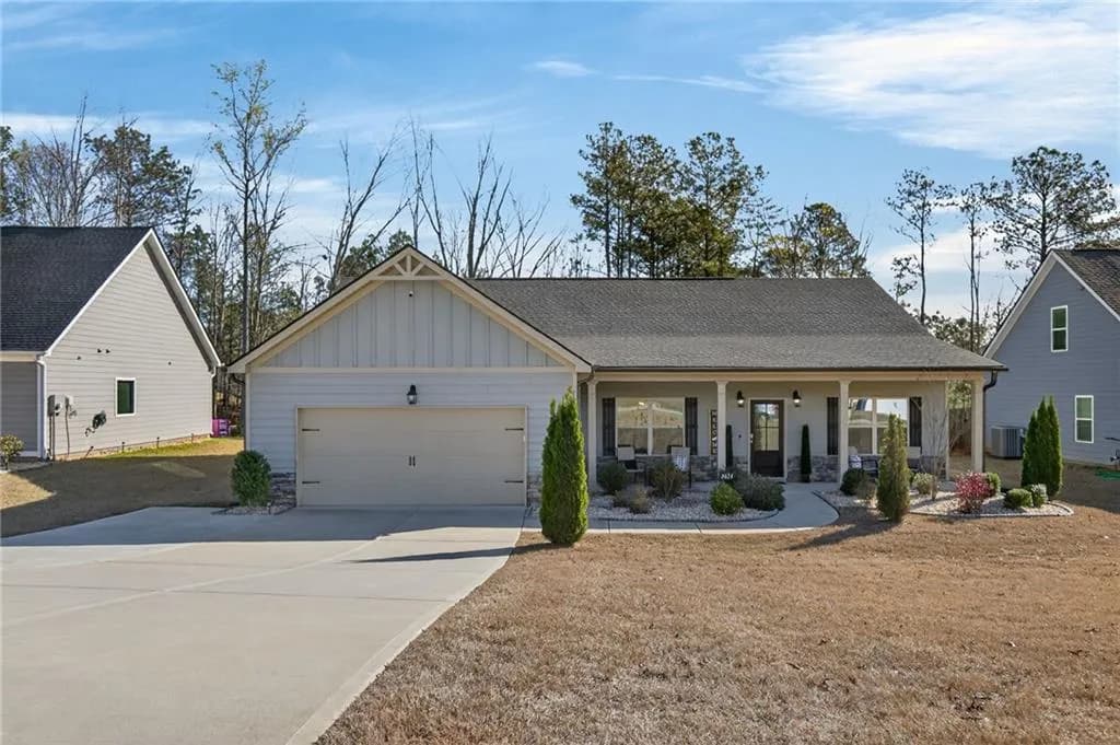 View of front facade featuring covered porch, roof with shingles, board and batten siding, concrete driveway, and an attached garage