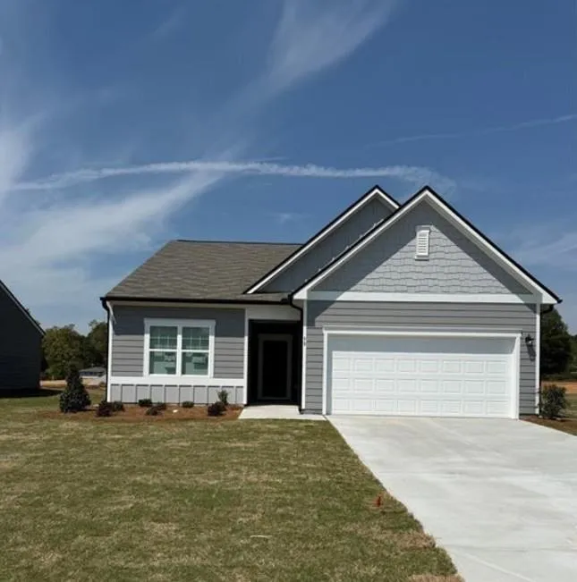 View of front of home with an attached garage, a front yard, and driveway