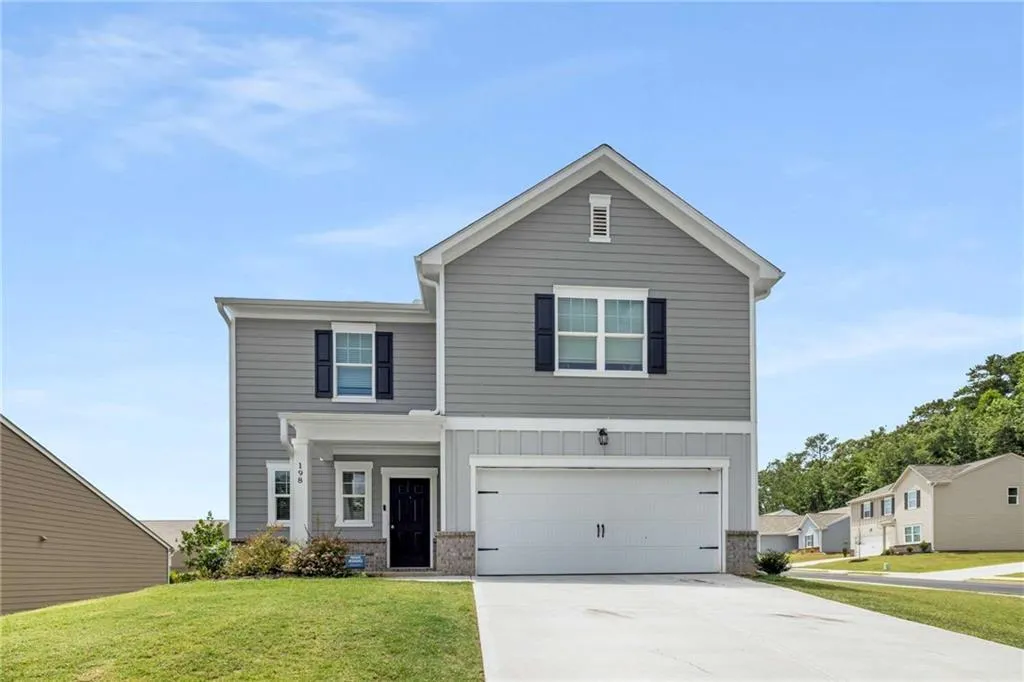 View of front of home with a front yard, concrete driveway, an attached garage, and board and batten siding