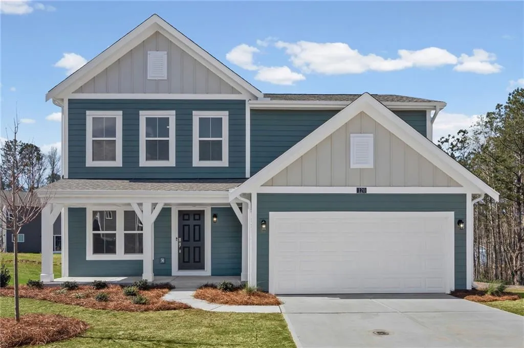 View of front of home with board and batten siding, covered porch, concrete driveway, and a front lawn