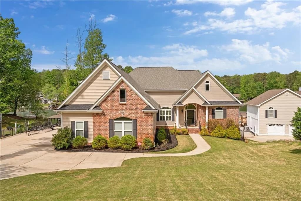 Traditional-style home with a front yard, brick siding, and roof with shingles