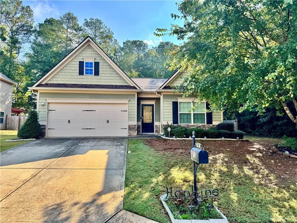 View of front of property with stone siding, concrete driveway, and a front yard