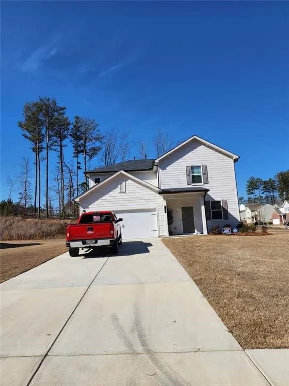 Traditional-style home with concrete driveway, a garage, a front yard, and a porch
