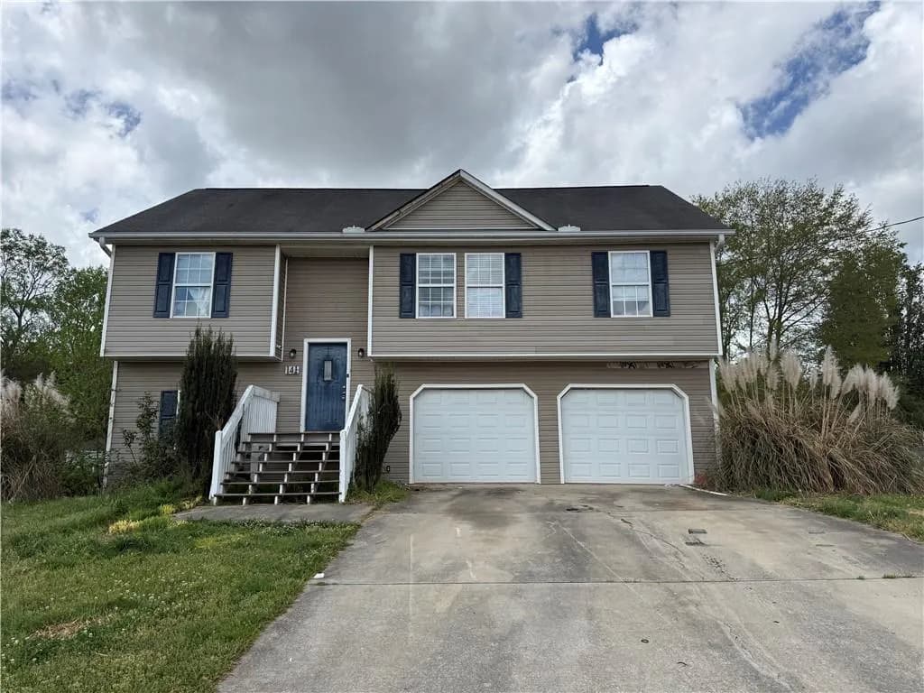 Bi-level home featuring concrete driveway, a garage, and a front lawn