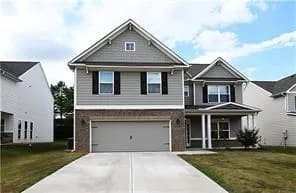 View of front of house featuring a front yard, an attached garage, driveway, and a porch