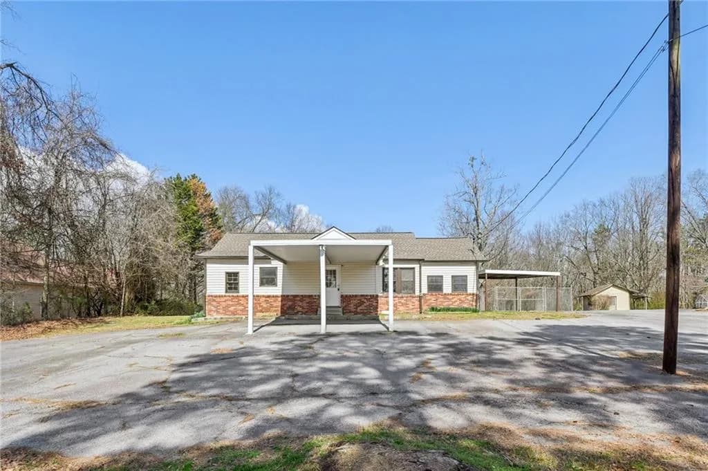 View of front of house with driveway, stone siding, covered porch, a carport, and a shingled roof
