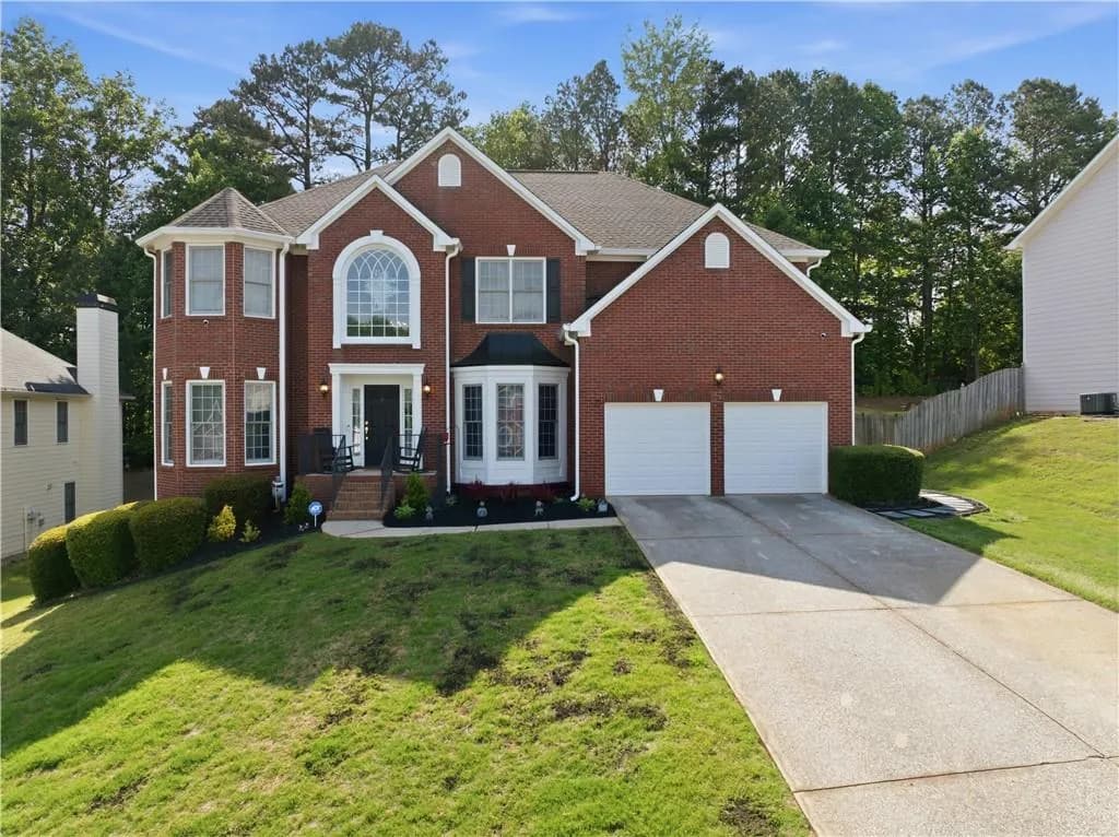 Brick-front exterior featuring a two-car garage, an arched window above the main entry, and a prominent bay window