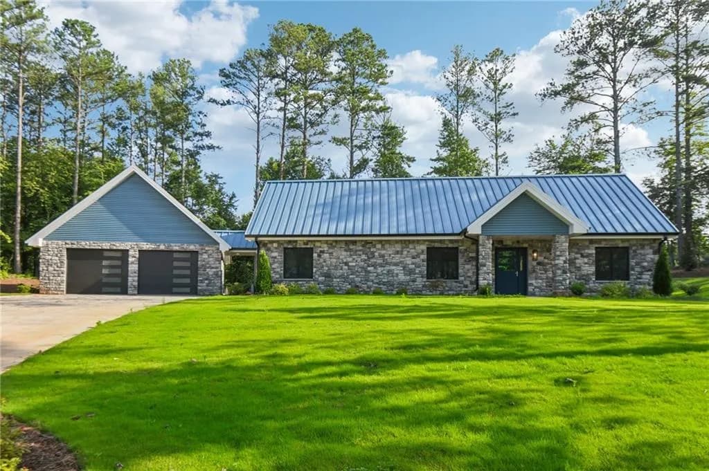 View of front of house with stone siding, a front yard, and a metal roof