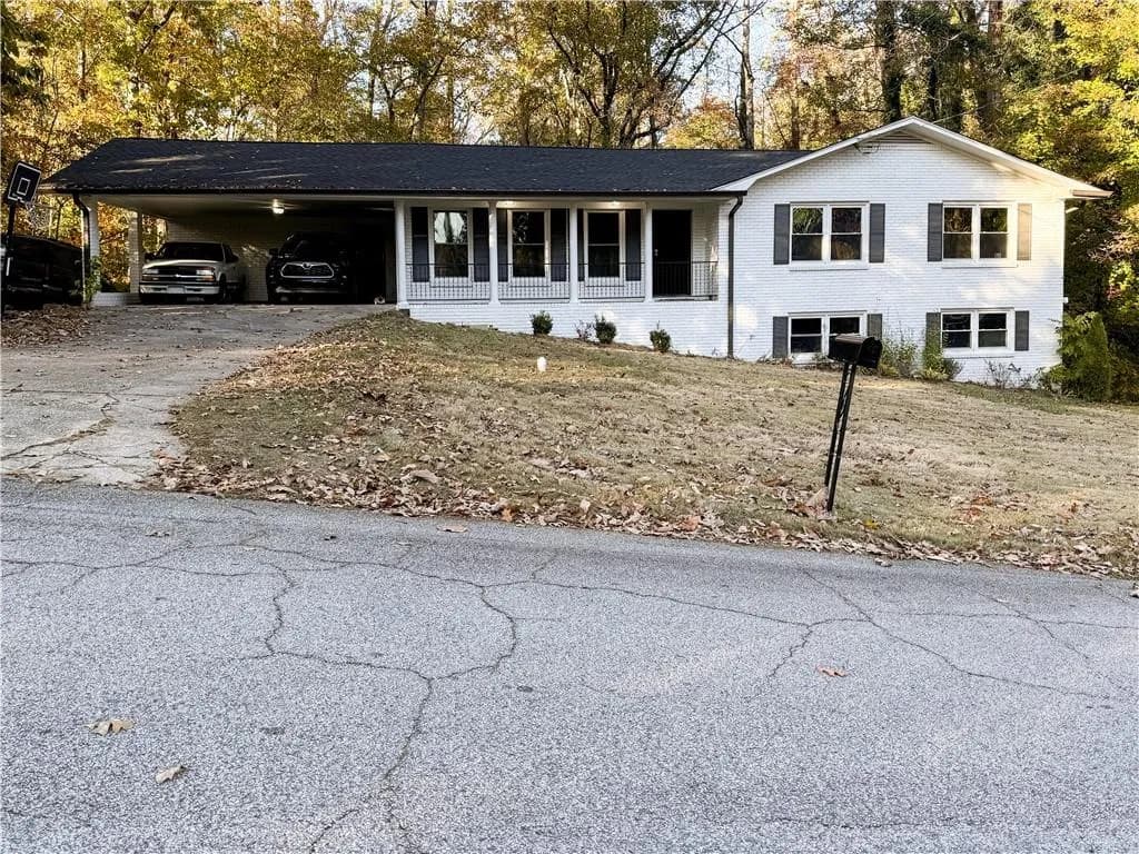 Single story home with a carport, brick siding, a porch, asphalt driveway, and a front lawn