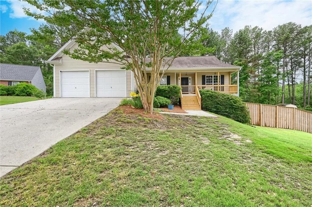 Ranch-style exterior with beige siding, a covered front porch, and a two-car garage