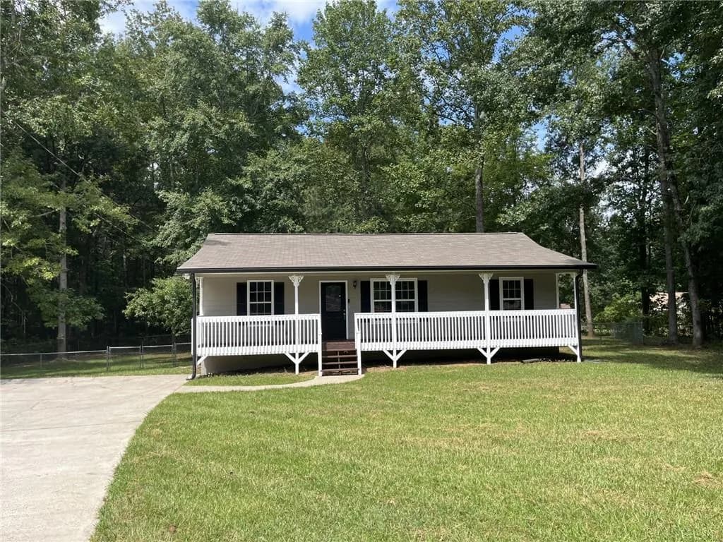 View of front facade featuring covered porch, view of scattered trees, concrete driveway, and roof with shingles