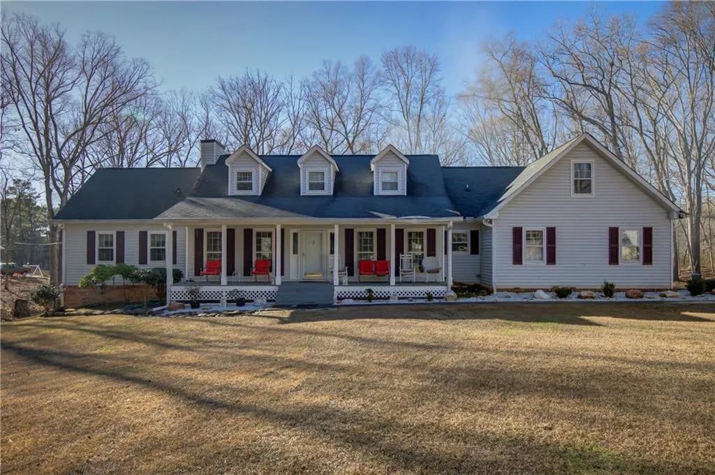 Cape cod house with a porch, a front yard, and a chimney